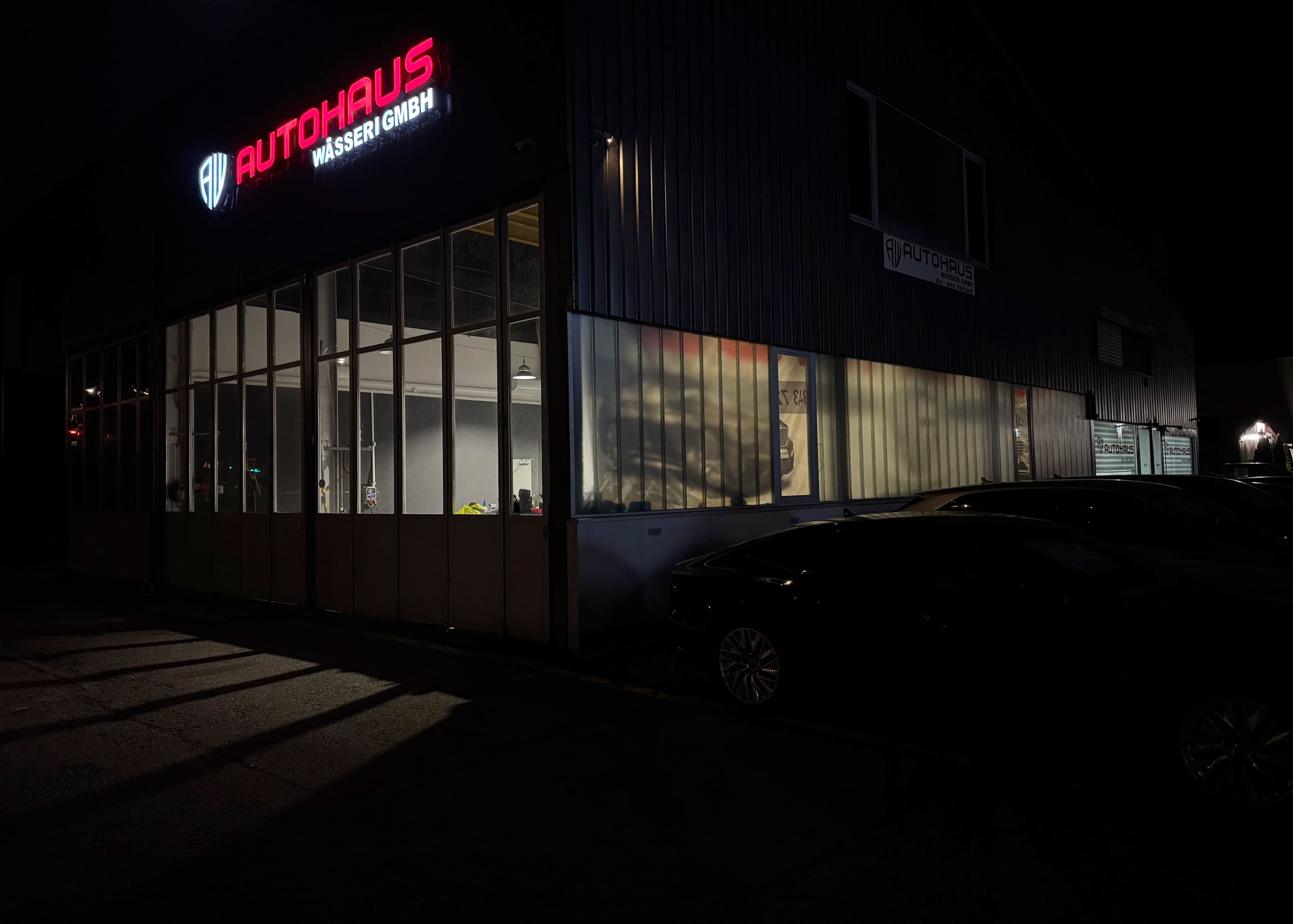 Das Autohaus Wässeri bei Nacht: Leuchtschrift und die beleuchtete Glasfront des Showrooms